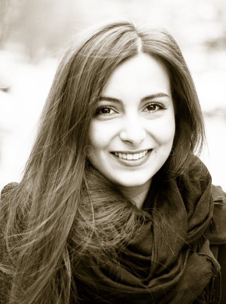 Sepia-toned portrait of a smiling woman with long hair and a scarf