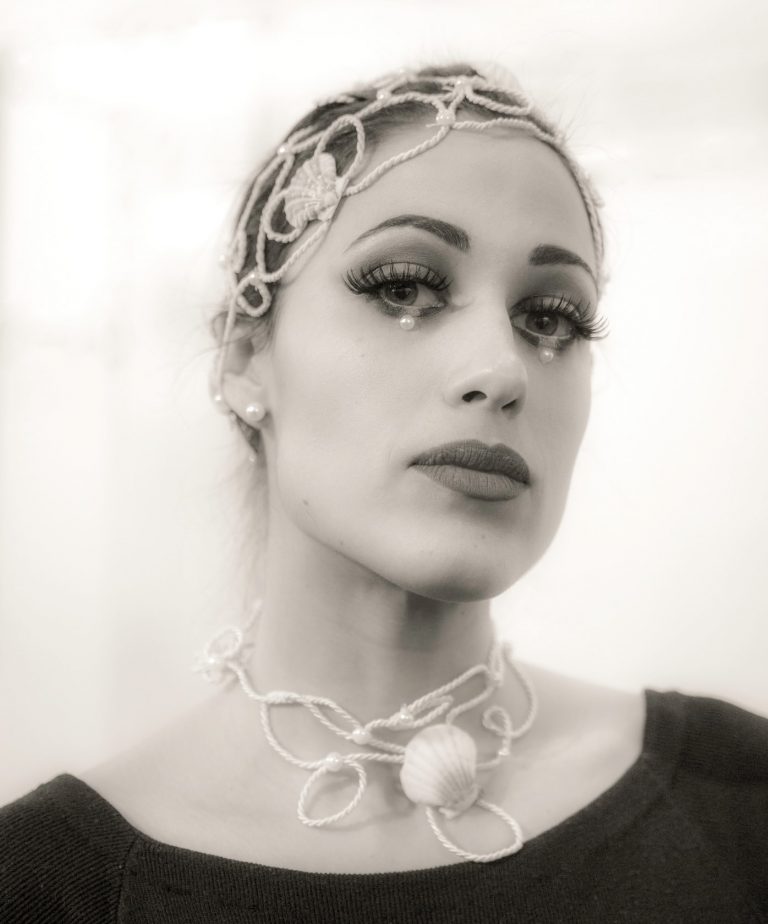 Black and white portrait of a woman wearing an ornate headpiece and necklace