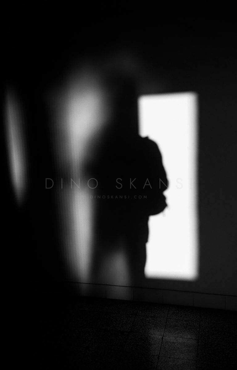 Black and white photo of a silhouetted figure beside a bright doorway