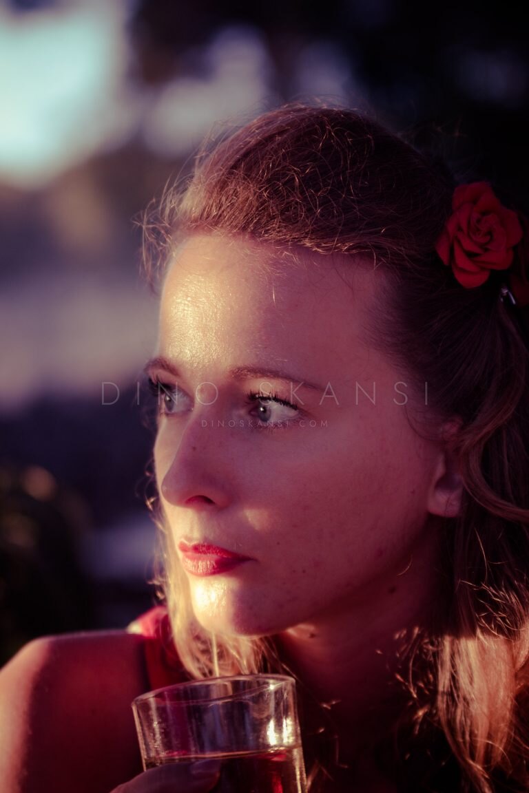 Colour portrait of a woman with a red flower in her hair in warm side light