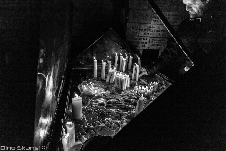 Black and white photo of candles burning at a shrine