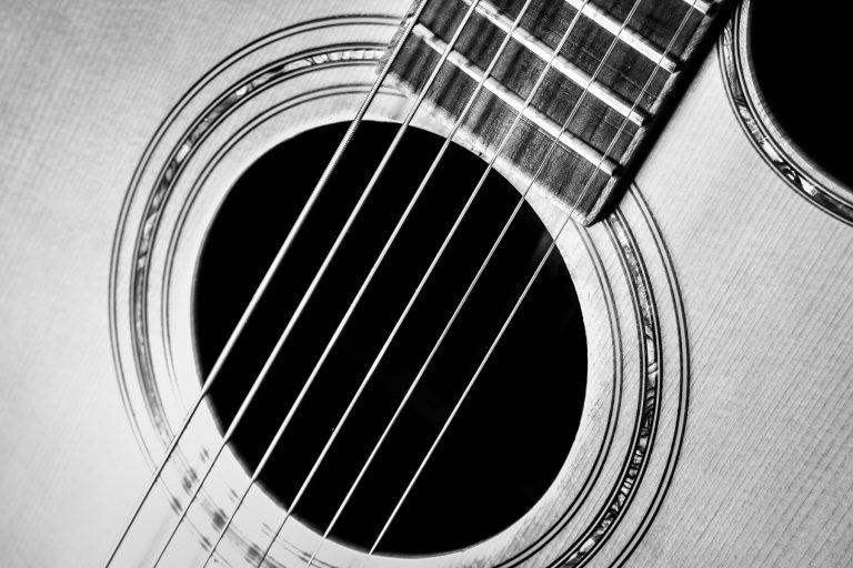 Black and white close-up of an acoustic guitar sound hole and strings