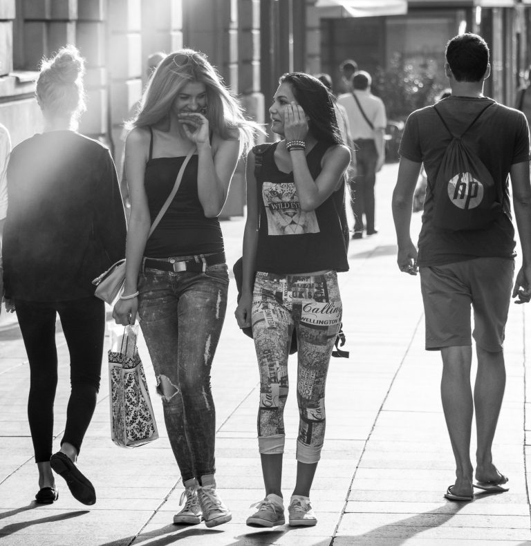 Colour street photo of a group of young people walking away in sunlight