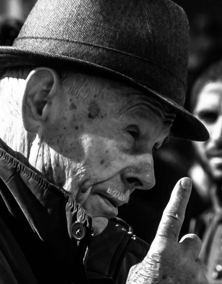 Black and white close-up portrait of an elderly man in a bowler hat, in profile