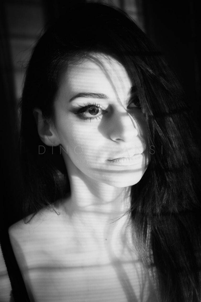 Black and white portrait of a woman with dark hair and shadows falling across her face
