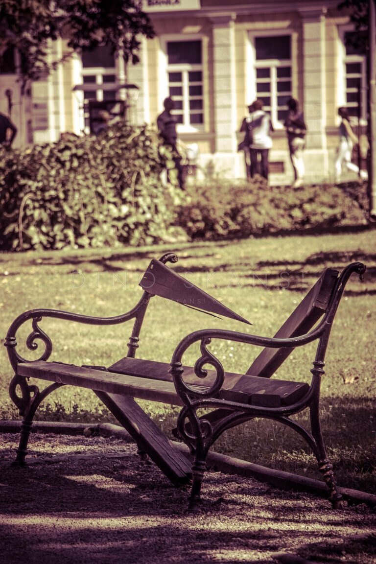 Sepia-toned photo of a wrought-iron park bench on a lawn