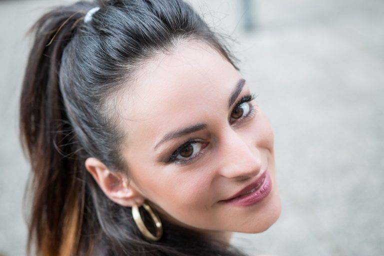 Colour close-up portrait of a smiling woman with hoop earrings