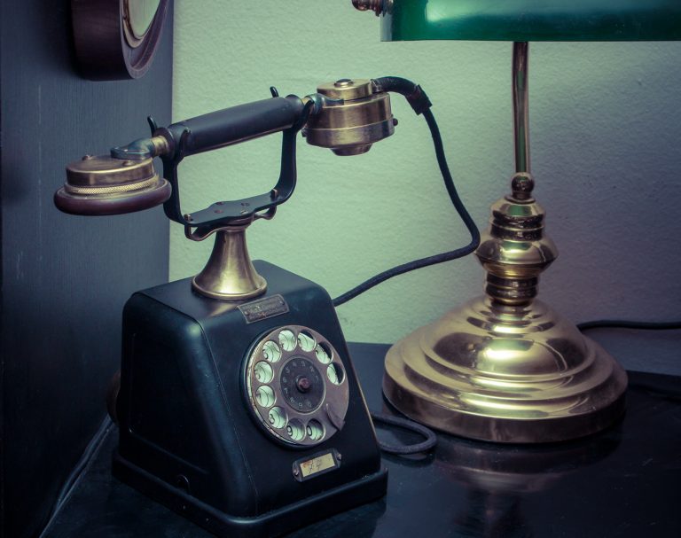 Vintage rotary telephone beside a brass desk lamp
