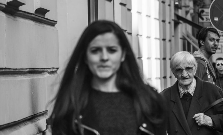 Black and white street photo of a woman with long dark hair walking towards the camera