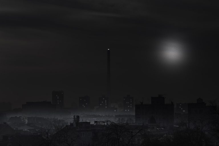 Dark black and white night view of a city skyline with a tower