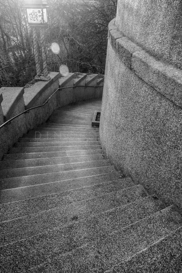 Black and white photo of a cobbled path curving along a stone wall