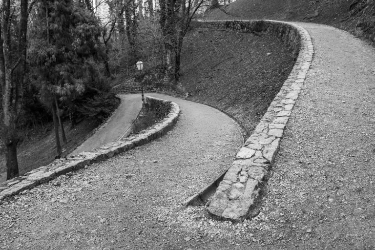 Black and white photo of a winding park path with stone edging