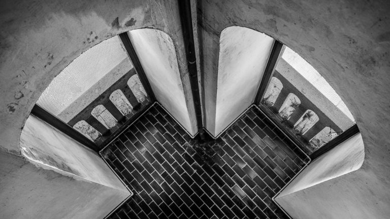 Black and white symmetrical view of curved architectural shapes above a tiled surface