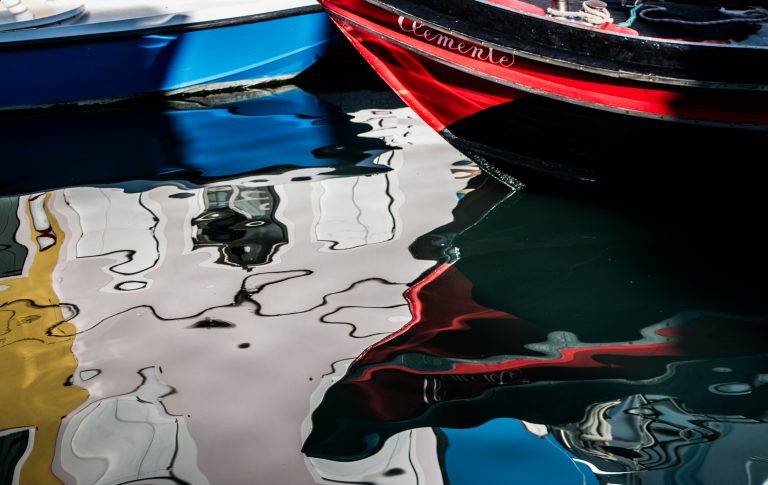 Colourful boats reflected in canal water in Venice