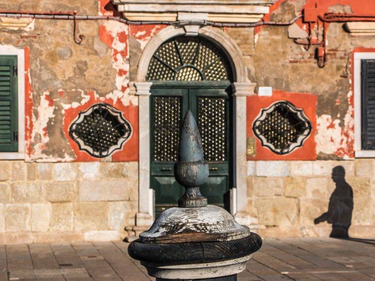 Weathered Venetian doorway with ornate windows and a stone wellhead