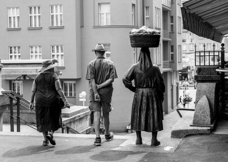 Colour street photo of people carrying baskets on their heads in a city street
