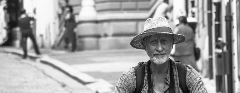 Black and white street portrait of a bearded man in a straw hat