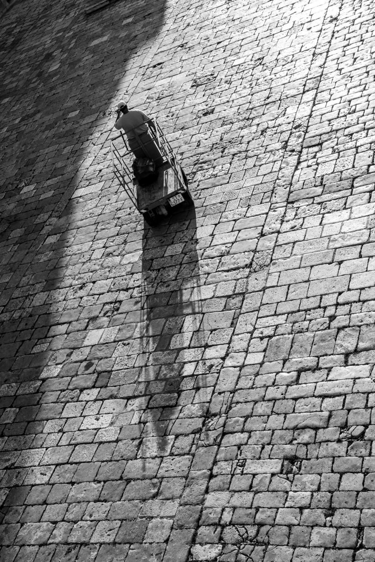 Black and white photo of a wall-mounted lamp on a brick wall