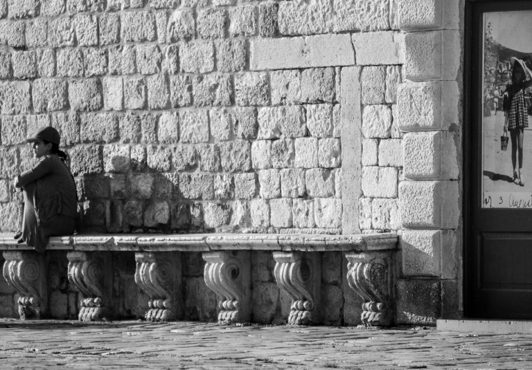Black and white photo of stone benches along an old stone wall
