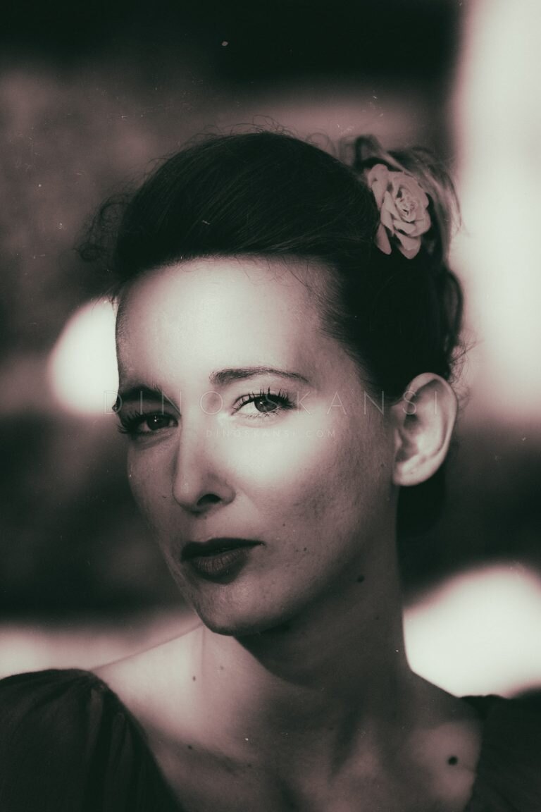 Toned portrait of a woman with a flower in her hair and dark lipstick