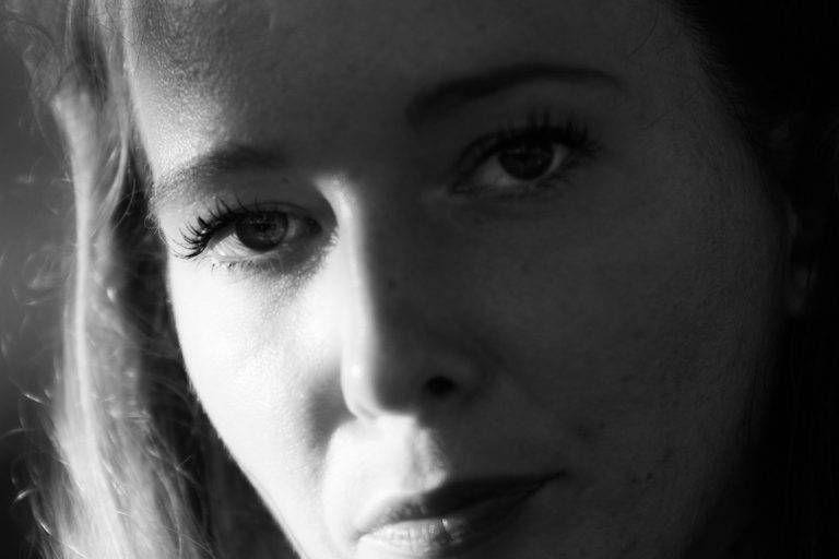 Black and white close-up of a woman's face half in shadow