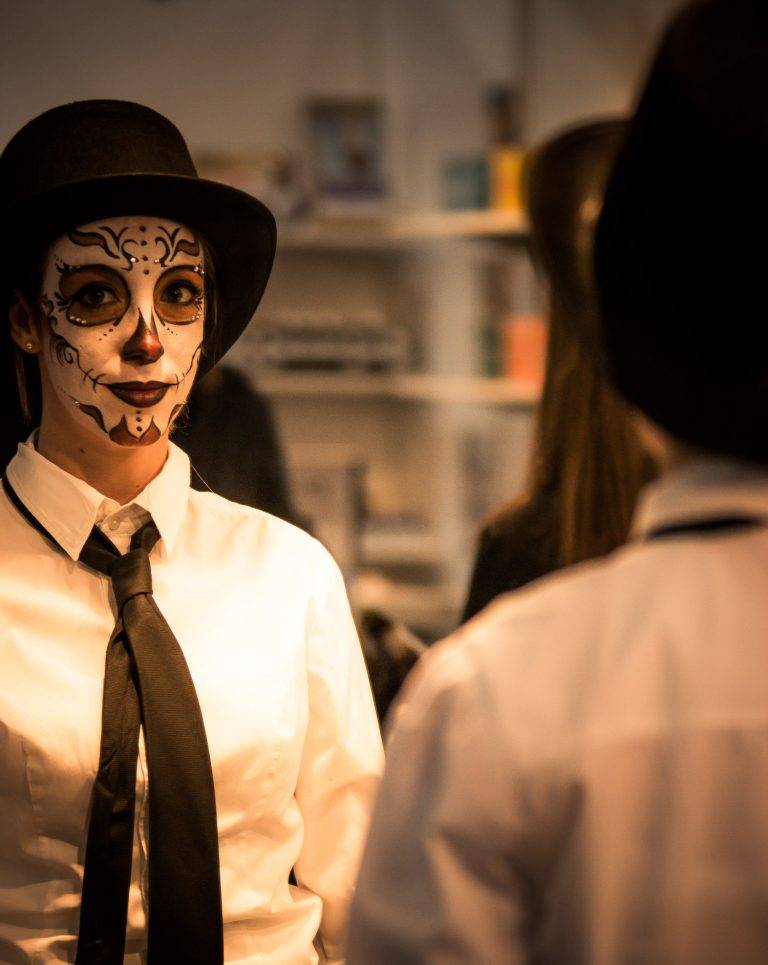 Colour portrait of a person in sugar-skull make-up wearing a top hat and tie