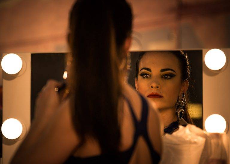 Colour backstage photo of a woman with a ponytail seen from behind, facing another woman