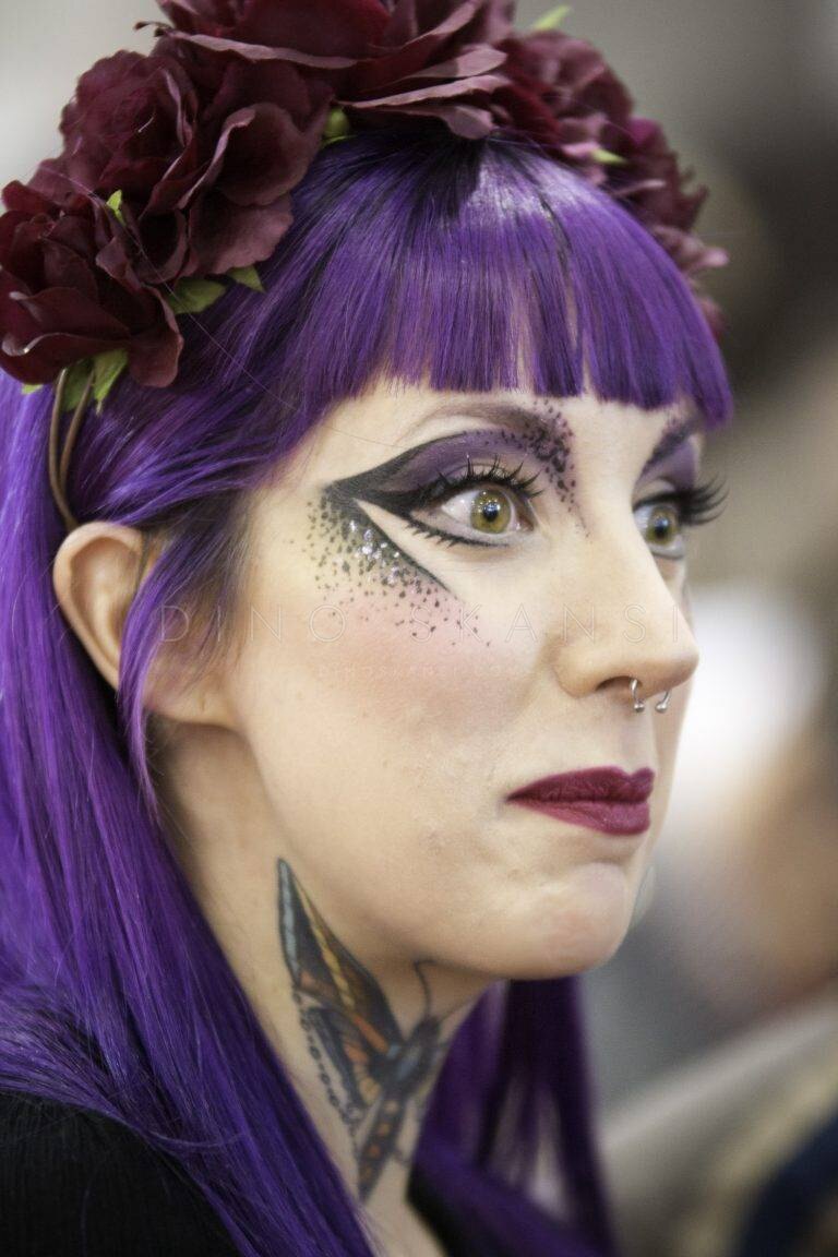 Colour profile portrait of a woman with purple hair and artistic eye make-up