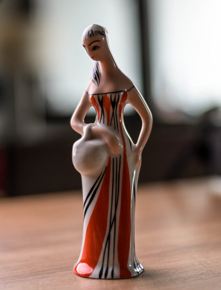 Ceramic figurine of a woman carrying a jug, photographed on a wooden table