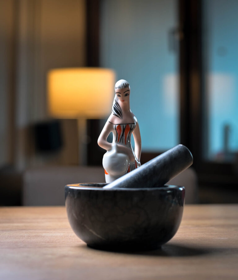 Stone mortar and pestle with a ceramic figurine in the background