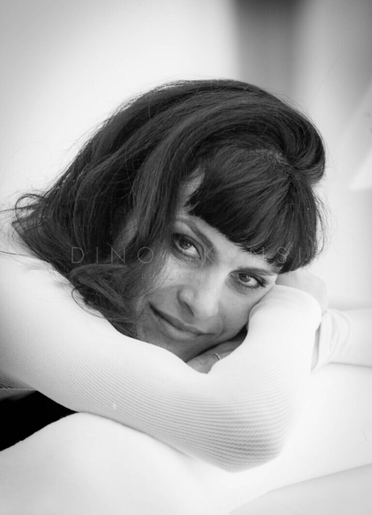 Black and white portrait of a woman with a bob haircut resting her head on her arms