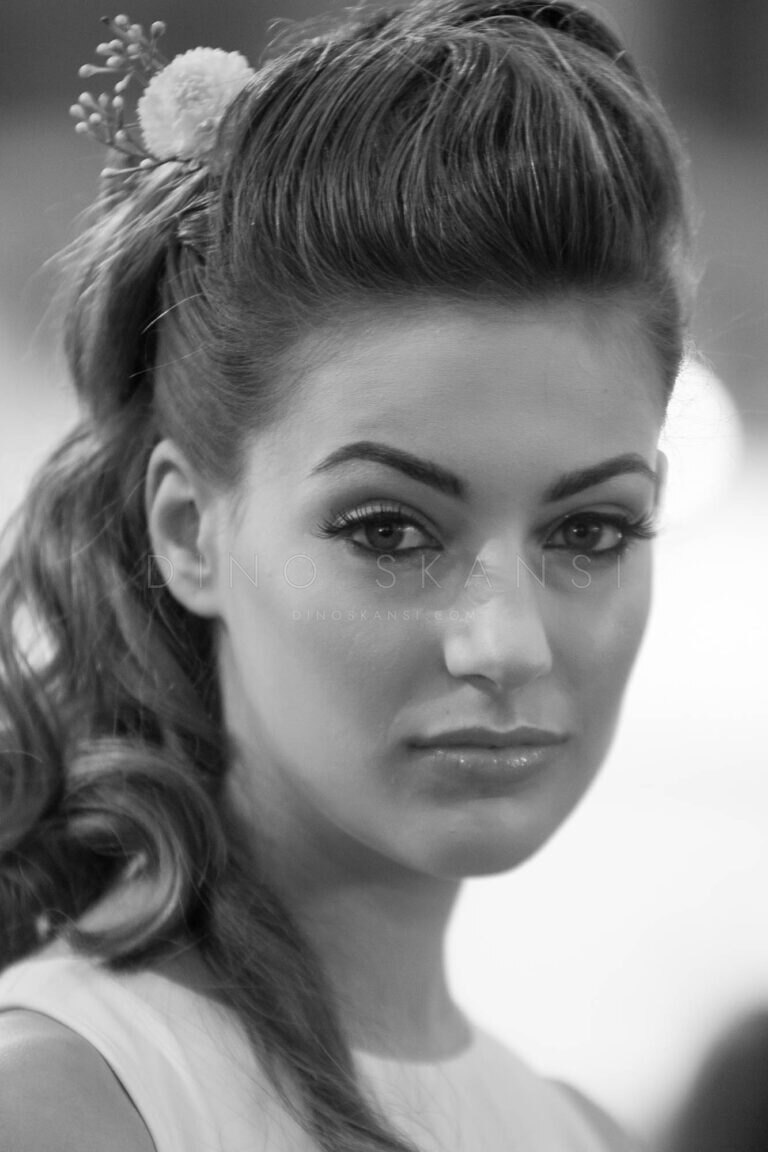 Black and white close-up portrait of a woman with curled hair looking at the camera