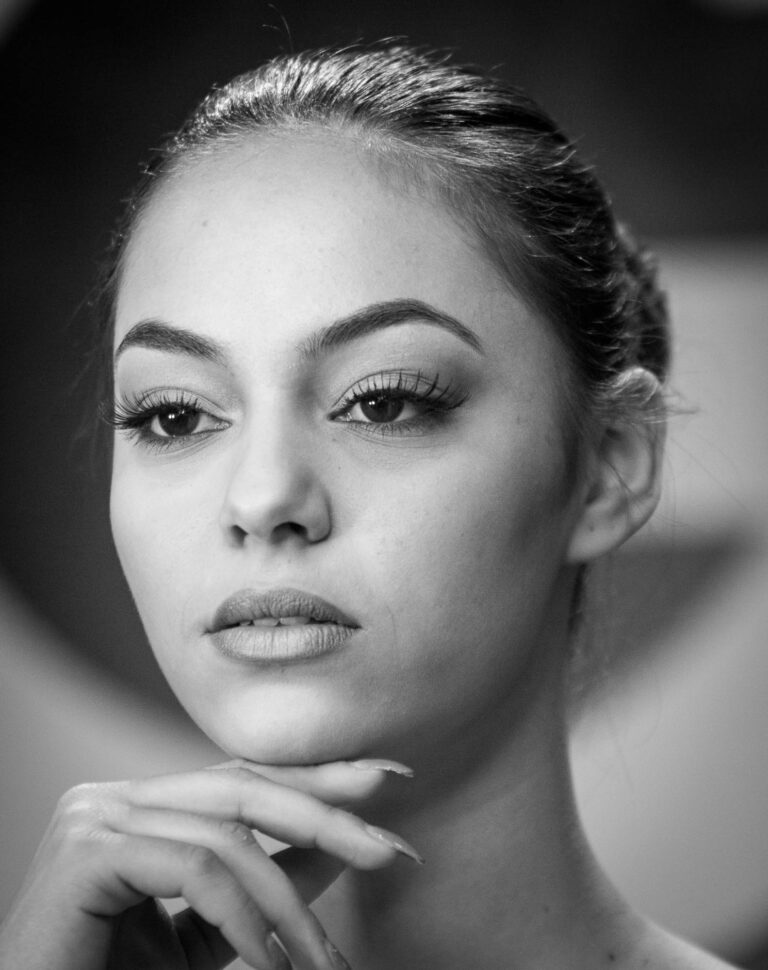 Black and white portrait of a woman with braided hair resting her chin on her hand