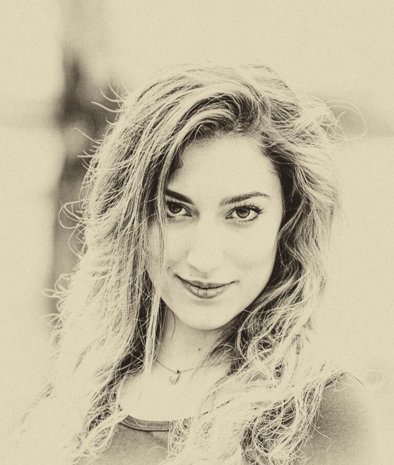 Sepia-toned portrait of a smiling woman with windswept hair