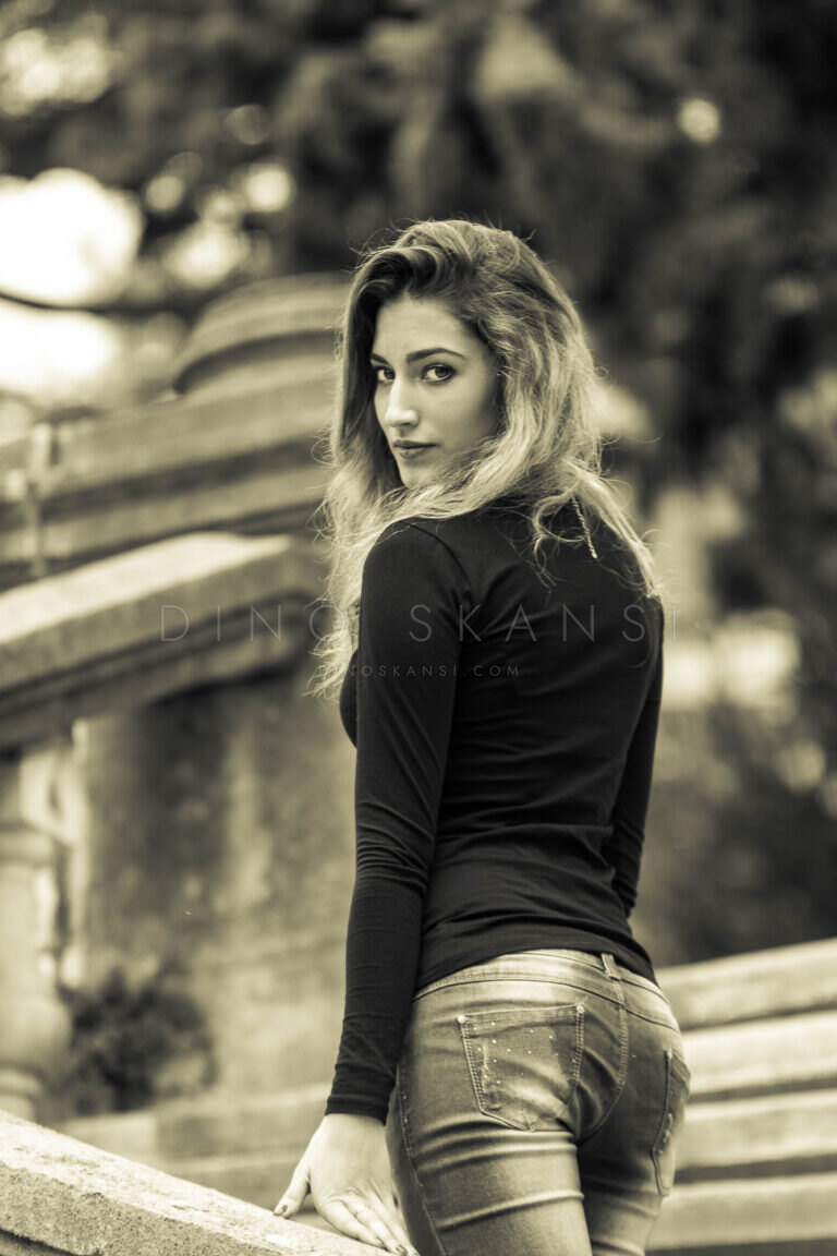 Toned portrait of a woman in black looking back over her shoulder in a park
