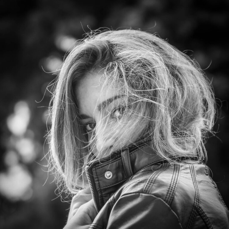 Black and white portrait of a woman with wind-blown hair covering part of her face