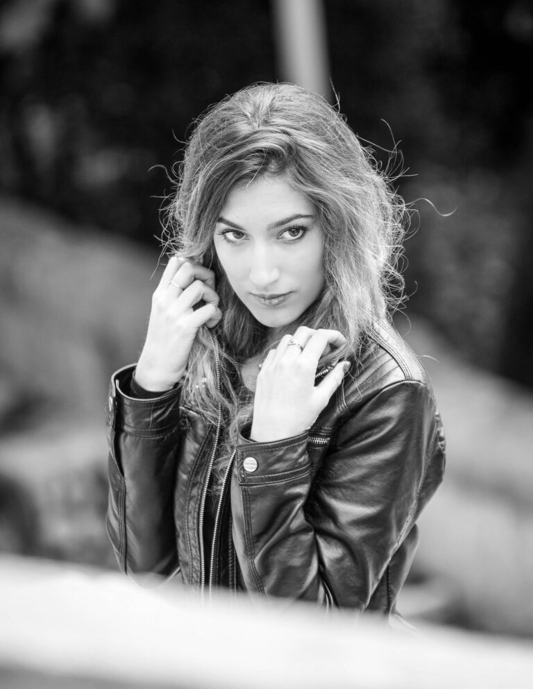 Black and white portrait of a woman in a leather jacket touching her hair