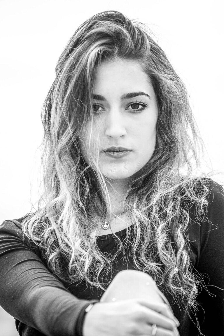 Black and white portrait of a woman with long wavy hair leaning forward