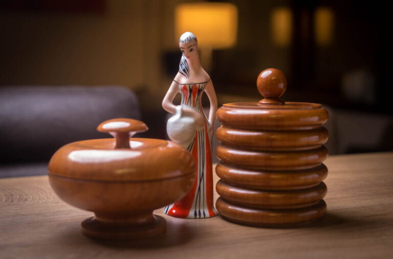 Ceramic figurine standing between carved wooden boxes