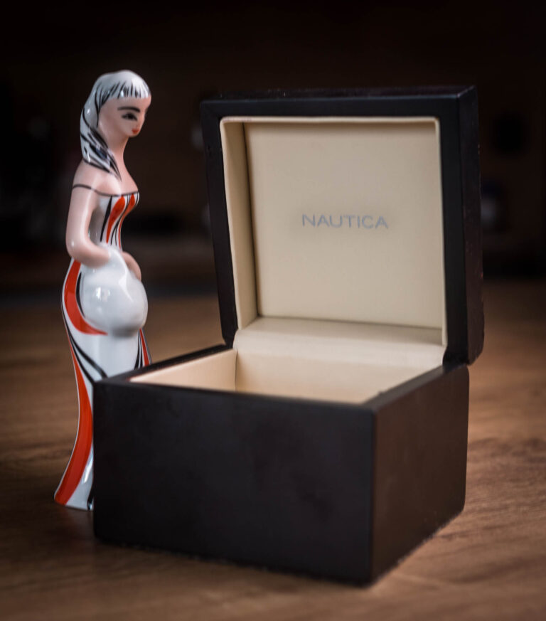 Ceramic figurine next to an open dark jewellery box