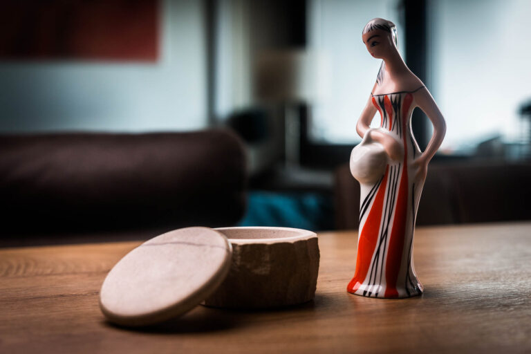 Ceramic figurine with a round wooden box on a table