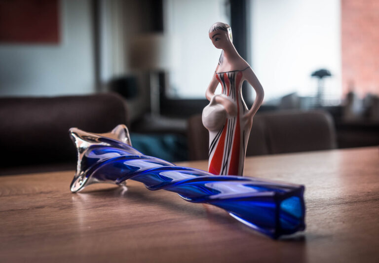 Ceramic figurine beside a blue glass object on a wooden table