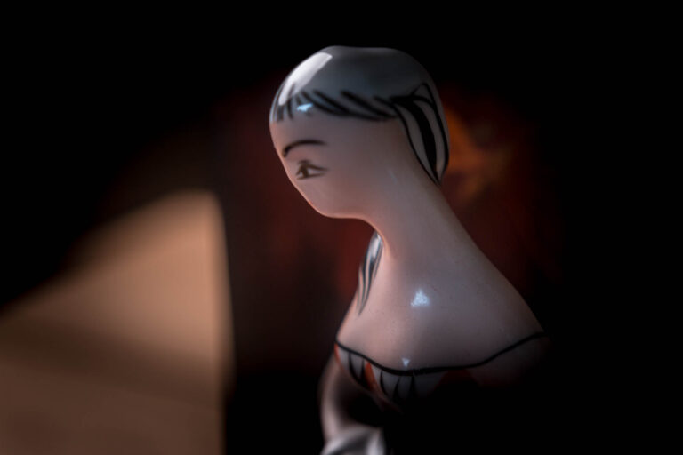 Ceramic figurine in profile against a dark background